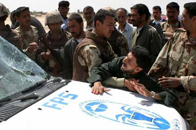 Soldados iraquíes, junto a un coche policial tiroteado ayer por  marines  cuando se acercaba a un control en Nayaf.