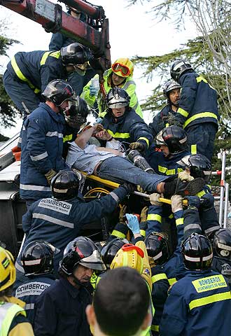 Un grupo de bomberos saca a un herido del autocar siniestrado.