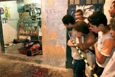 Vecinos del municipio de Nova Iguaçú, en Río de Janeiro, observan los cádaveres de tres personas asesinadas ayer.