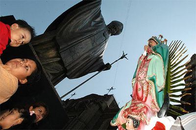Un grupo de fieles reza ante la estatua de Juan Pablo II junto a la basílica de Guadalupe, en la capital mexicana.