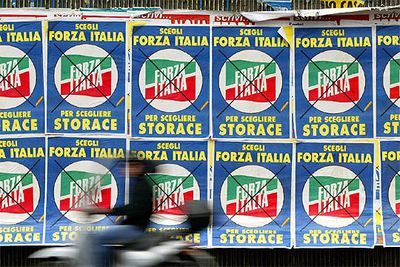 Un motociclista pasa junto a carteles electorales en una calle de Roma.