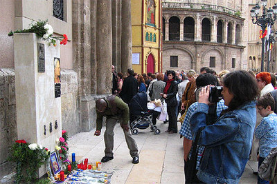 Un hombre se dispone a colocar una vela junto a las fotografías del Papa, ayer, en la plaza de la Virgen de Valencia.