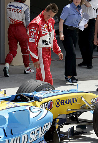 Michael Schumacher mira los neumáticos del Renault de Fernando Alonso.
