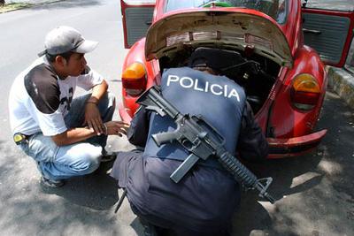 Un policía armado con un fusil examina el maletero de un coche en Ciudad de México.