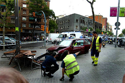 Un policía y dos sanitarios observan el lugar del accidente con el banco en primer término y el coche maltrecho detrás.