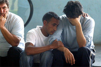 El padre del bebé (a la derecha) era ayer consolado por familiares y vecinos a las puertas del hospital.