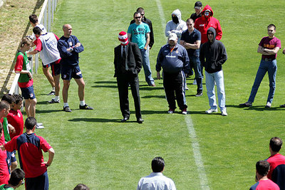 Los  ultras,  con Fran, el del traje, y Portu, con gorra, al frente insultando a los jugadores ante la mirada reprobatoria de Bastón, cruzado de brazos.