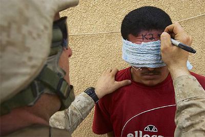 Un  marine  estadounidense escribe un número de identificación en la frente de un prisionero iraquí.