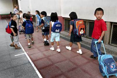Alumnos de una escuela pública de Barcelona con sus mochilas y carteras con ruedas.