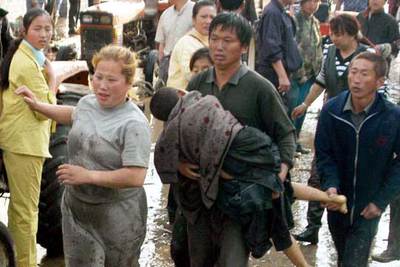 Un hombre lleva en brazos a un niño rescatado en la escuela destruida por la riada.