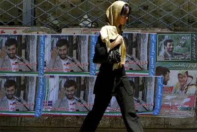 Una mujer pasa por delante de carteles del candidato Mahmud Ahmadineyad, ayer en Teherán.