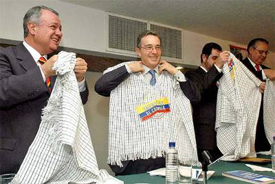 Álvaro Uribe (segundo por la izquierda) se pone un poncho 