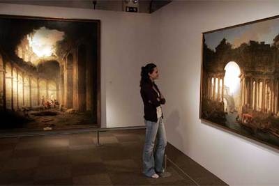 Una visitante, ante dos de las pinturas del Coliseo de Roma realizadas por el paisajista francés Hubert Robert a mediados del siglo XVIII.