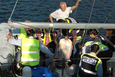 Agentes de policía descargan los 500 kilos de cocaína en presencia del único tripulante (al fondo, de blanco).