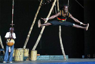Un músico toca la kora mientras un bailarín ejecuta una acrobacia durante la presentación del espectáculo del Circus Baobab  Le singe de Saudieu.