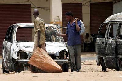 Dos hombres observan los vehículos destrozados por los manifestantes tras los enfrentamientos de ayer en Jartum.