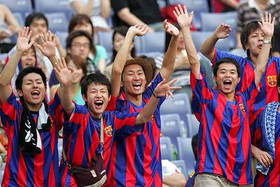 Jóvenes vestidos con la camiseta azulgrana apoyan al Barcelona durante su partido en Yokohama.