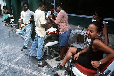 Un grupo de jóvenes hispanos, en una peluquería al aire libre en una calle de Nueva York. rnrnEl voto de esta minoría tiene cada día más peso en la ciudad, hasta el punto rnrnde que ya casi es determinante a la hora de decidir la permanencia en el cargo de un concejal.