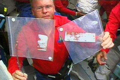 El astronauta Andy Thomas muestra las dos juntas de las losetas del  Discovery e xtraídas el pasado miércoles.