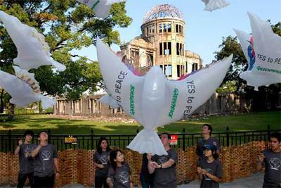 Miembros de Greenpeace sostienen globos frente a la cúpula de Hiroshima, la víspera del 60º aniversario de la explosión.