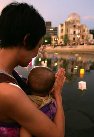 Una mujer japonesa sostiene a su hijo mientras reza por las víctimas de Hiroshima.