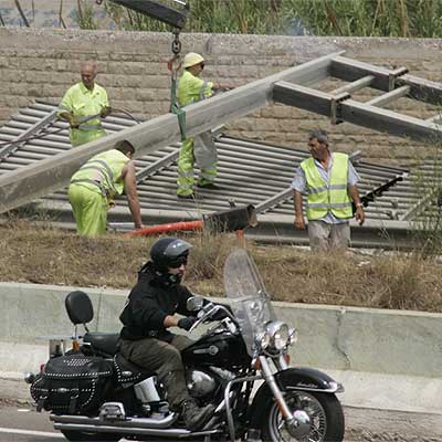 Unos operarios retiran la estructura del panel derribado por el camión en la V-30 de Valencia