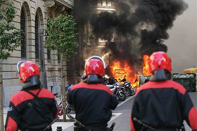 Tres  ertzainas  observan unos contenedores ardiendo en la calle Hondarribia, en el centro de San Sebastián, ayer por la tarde.rnrnJESÚS URIARTE