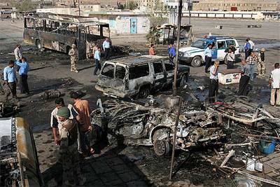 Policías y soldados iraquíes observan los restos de uno de los coches bomba que explotaron en Bagdad.
