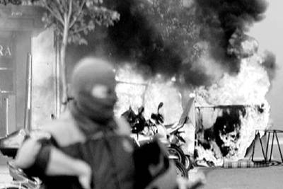 Un  ertzaina  pasa ante un contenedor incendiado durante los incidentes que siguieron a la manifestación de Batasuna.