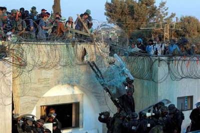 Colonos judíos se enfrentan a agentes antidisturbios israelíes desde el tejado de la sinagoga en el asentamiento de Gush Katif.