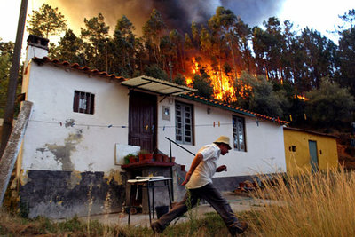Un hombre escapa del fuego que asedia su casa, cerca de Coimbra.