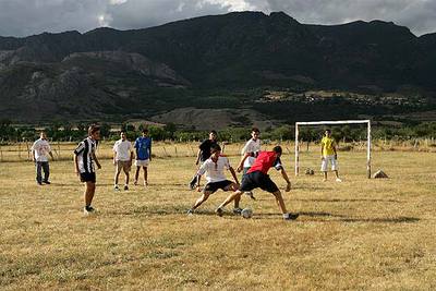 Los chicos del pueblo juegan con los veraneantes un partido de fútbol en  Riolago de Babia.
