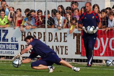 Casillas detiene un balón, en el entrenamiento de la selección, mientras Reina espera su turno.