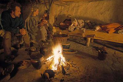 Una familia reunida alrededor de la hoguera en una de las chozas del pueblo de la edad del hierro en el Lejre Experimental Center.
