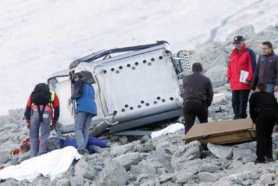 La policía analiza los restos de la cabina accidentada junto a los cuerpos cubiertos de dos de los muertos.
