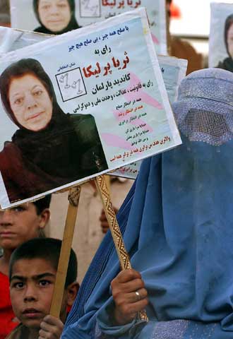 Una mujer con  burka  porta la foto de la candidata Suraia Perlilka.