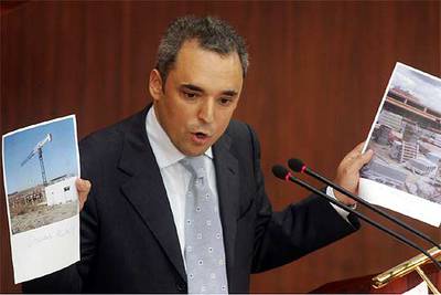 El líder socialista, Rafael Simancas, muestra durante el debate las fotos de dos colegios instalados en barracones.