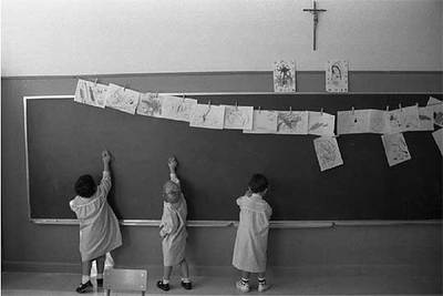 Unos niños dibujan en la pizarra en una clase de un colegio religioso.