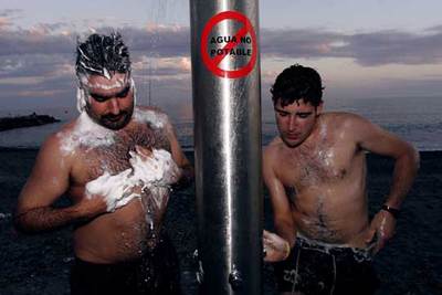 Dos agricultores se lavan en las duchas del paseo marítimo de la Mamola, en la costa de Granada.