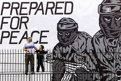 Un hombre y un niño, ante un mural en Belfast a favor del IRA donde se lee: 