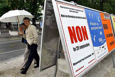 Una pareja pasa delante de varios carteles electorales de distintos partidos suizos en el centro de Ginebra.