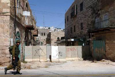 Muro instalado en una calle de Hebrón para proteger a los colonos donde una pintada dice: 