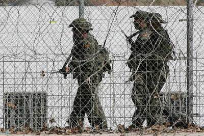 Tres legionarios pasan ante una garita junto a la valla fronteriza de Ceuta.
