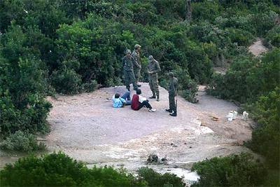 Cuatro soldados marroquíes interrogan a dos subsaharianos en los bosques de Bel Younech, a un kilómetro de Ceuta.