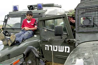 Un palestino de 13 años es utilizado como  escudo humano,  en abril de 2004, contra las pedradas de los manifestantes.