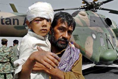 Un padre sostiene a su hijo en una base militar cercana a Islamabad tras ser evacuados de Muzaffarabad.