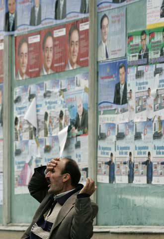 Un hombre gesticula ante propaganda electoral en  Bakú.