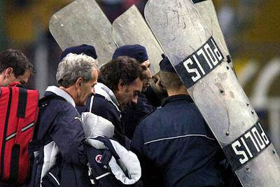 Parte del equipo técnico suizo es protegido al salir del campo anoche.