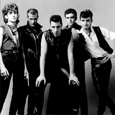 El cantante Loquillo, en el centro, y el guitarrista y compositor Sabino Méndez, apoyado en su hombro, con la banda al completo de Loquillo y Los Trogloditas.