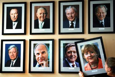 Una funcionaria coloca un retrato de la nueva canciller Angela Merkel a continuación del de su antecesor,  Gerhard Schröder,  en la sede de la Cancillería en Berlín.